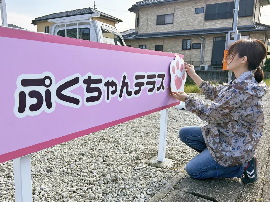 愛知県津島市でキッチンカーの「ぷくちゃんテラス」と営んでいるお客様の駐車場に置く自立看板のロゴマークを取り付けている施工写真です。