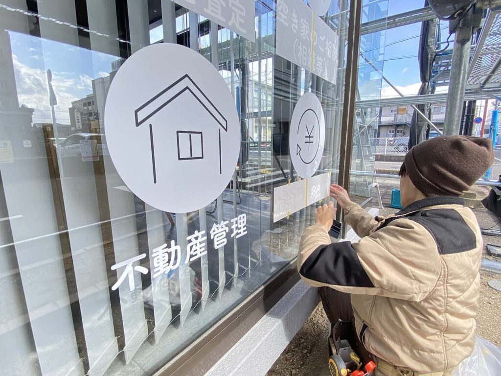 沖野不動産のガラスサインの施工中の写真です。